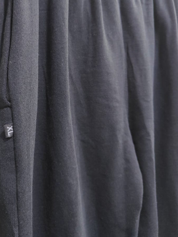 Dark gray heathered lounge pants hanging on a wooden hanger against a textured gray wall.