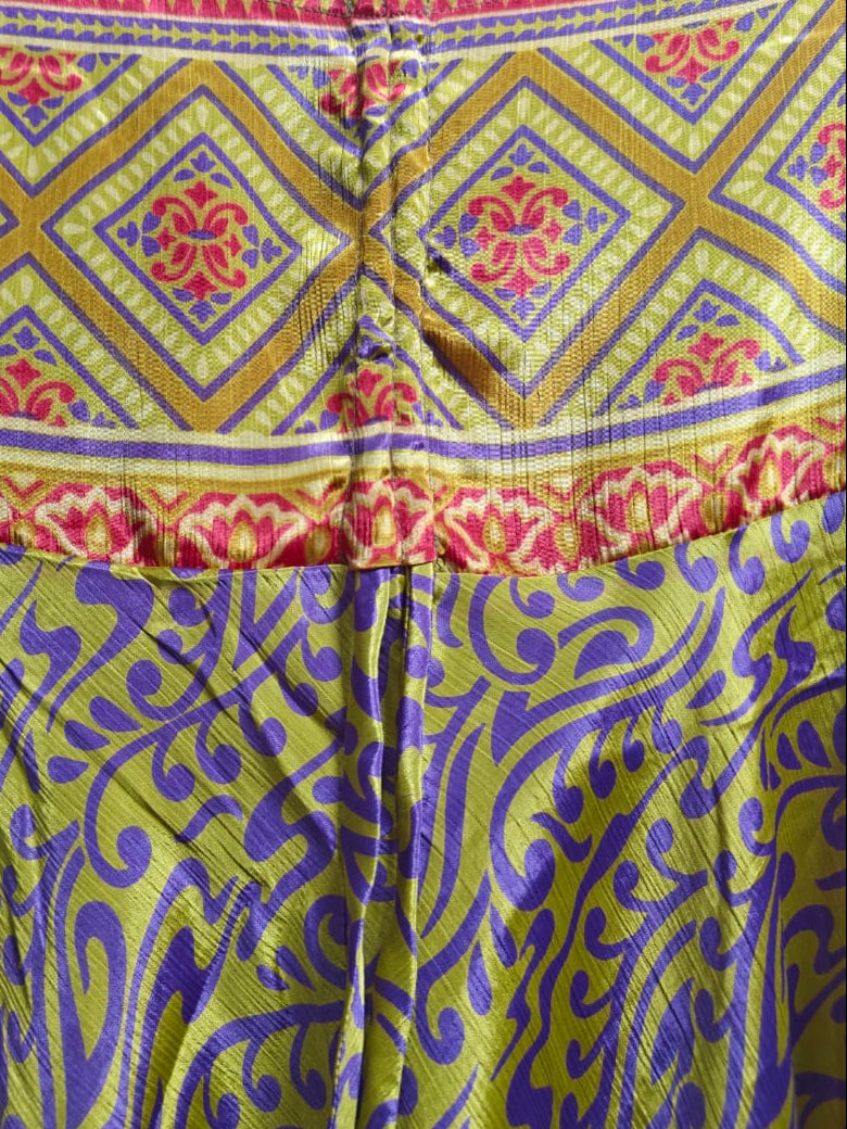 Close-up of a patterned garment or fabric panel with a geometric diamond design in yellow, red, and blue above a swirling paisley-like pattern in yellow and purple.