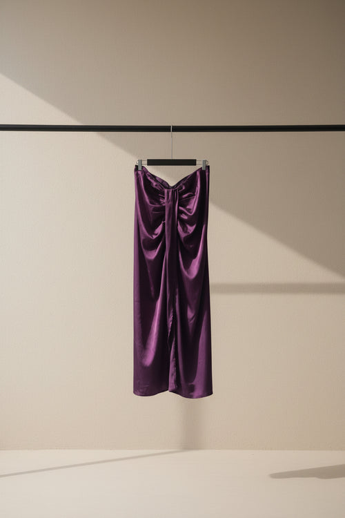 A draped purple satin or silk garment hanging from a wooden clothesline in an outdoor courtyard with potted plants and tree branches visible in the background.