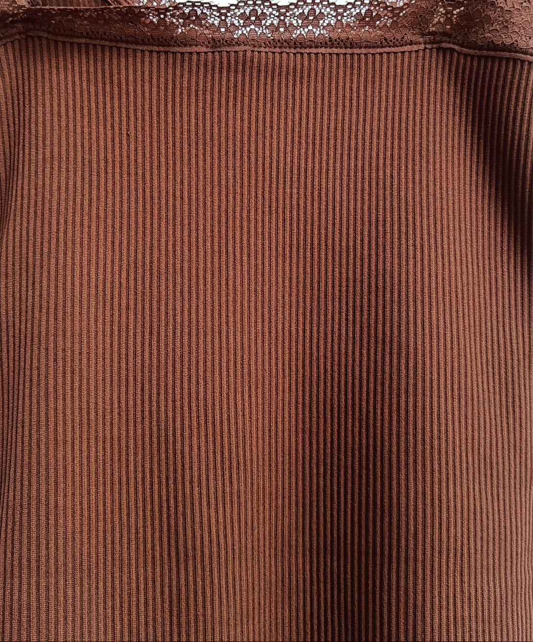 A close-up of a brown ribbed camisole top with delicate lace trim along the neckline and thin shoulder straps, shown against a plain light background.