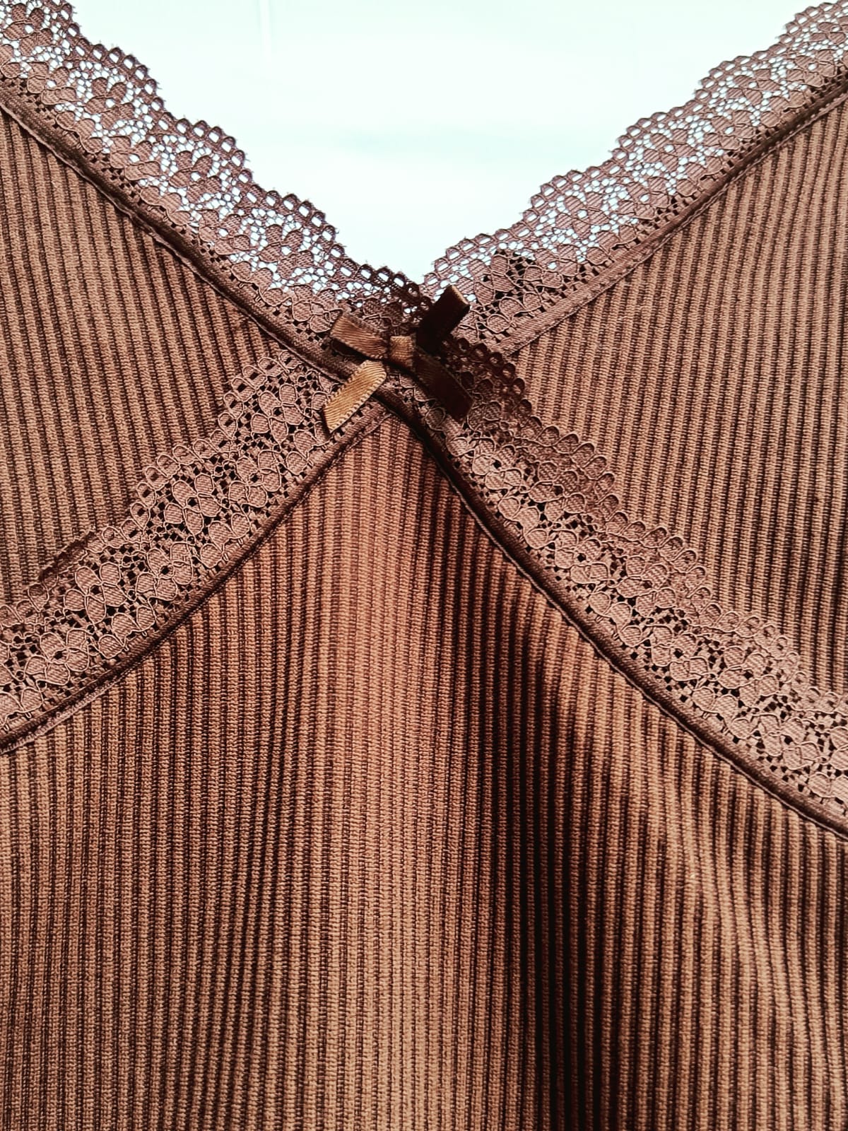 Close-up of a brown ribbed camisole top with matching lace trim and a small bow at the center neckline.