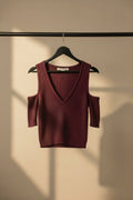 A ribbed knit cold-shoulder sweater in a deep burgundy or plum color, laid flat on a light off-white background. The brand name 'SWEATERS' is visible on the inner neck label.