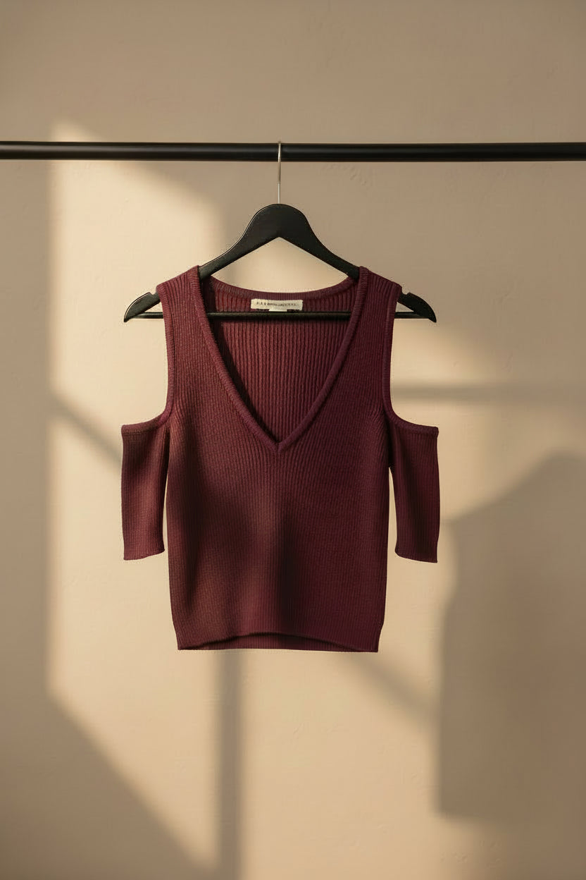A ribbed knit cold-shoulder sweater in a deep burgundy or plum color, laid flat on a light off-white background. The brand name 'SWEATERS' is visible on the inner neck label.