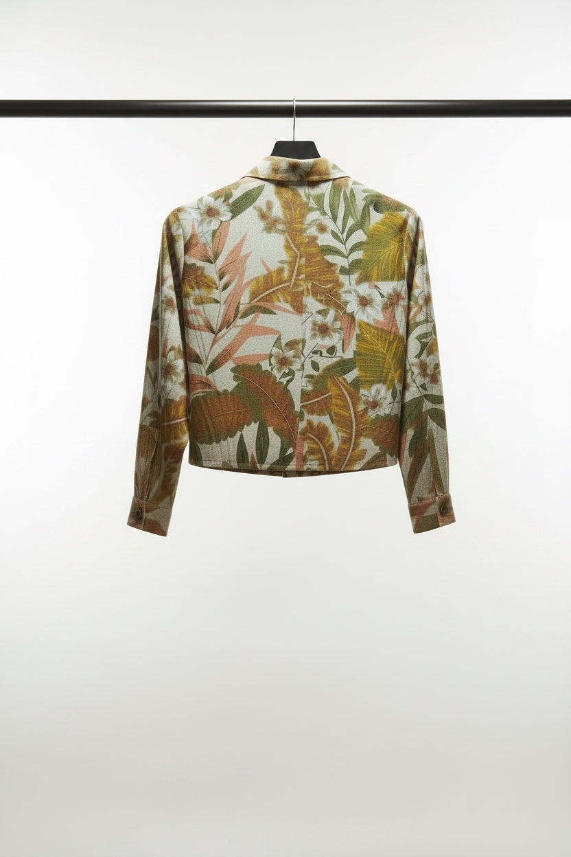 A long-sleeve button-up shirt with a tropical floral and leaf print, laid flat on a light gray background.