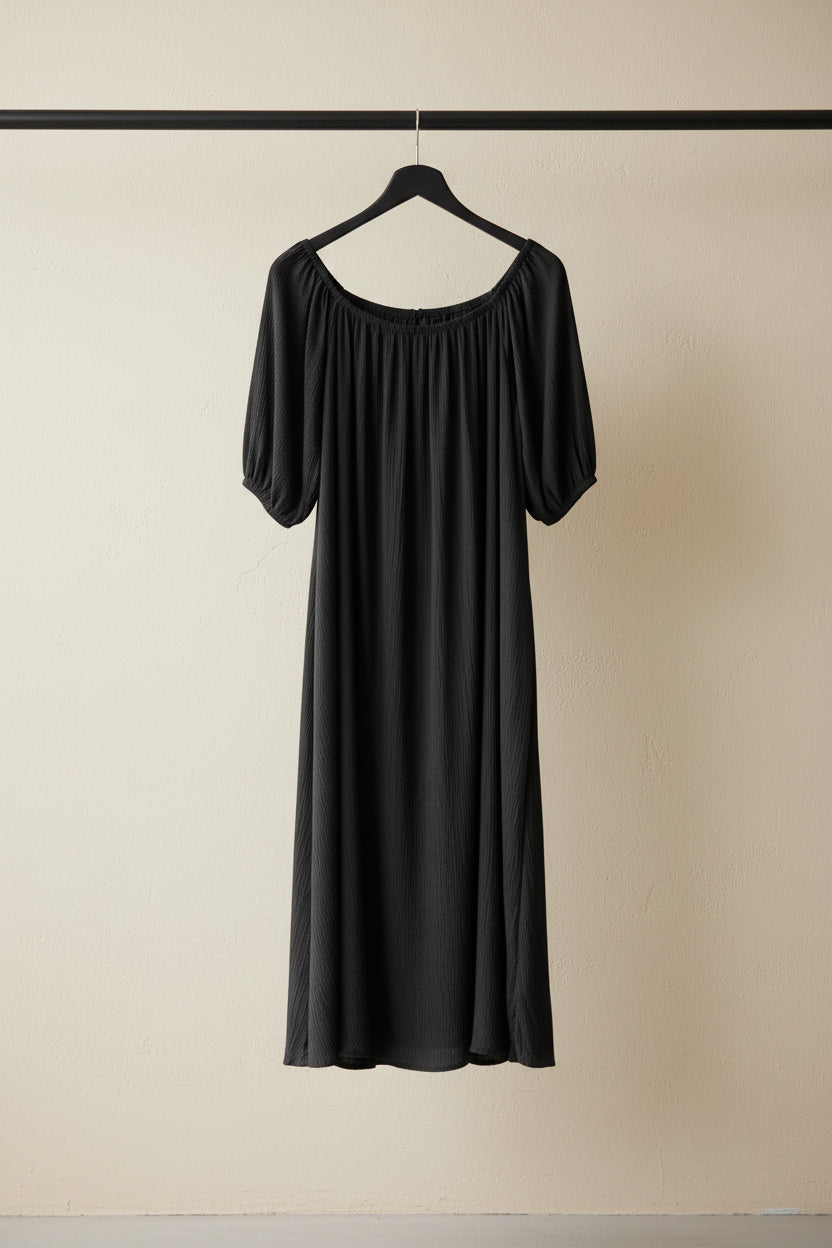 A dark charcoal gray off-the-shoulder dress with short puff sleeves, hanging on a wooden hanger against a neutral gray fabric backdrop.