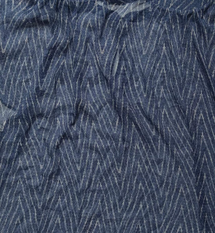 A loose-fitting, short-sleeved top in dark indigo blue with a white zigzag stripe pattern, laid flat on a white fabric background.