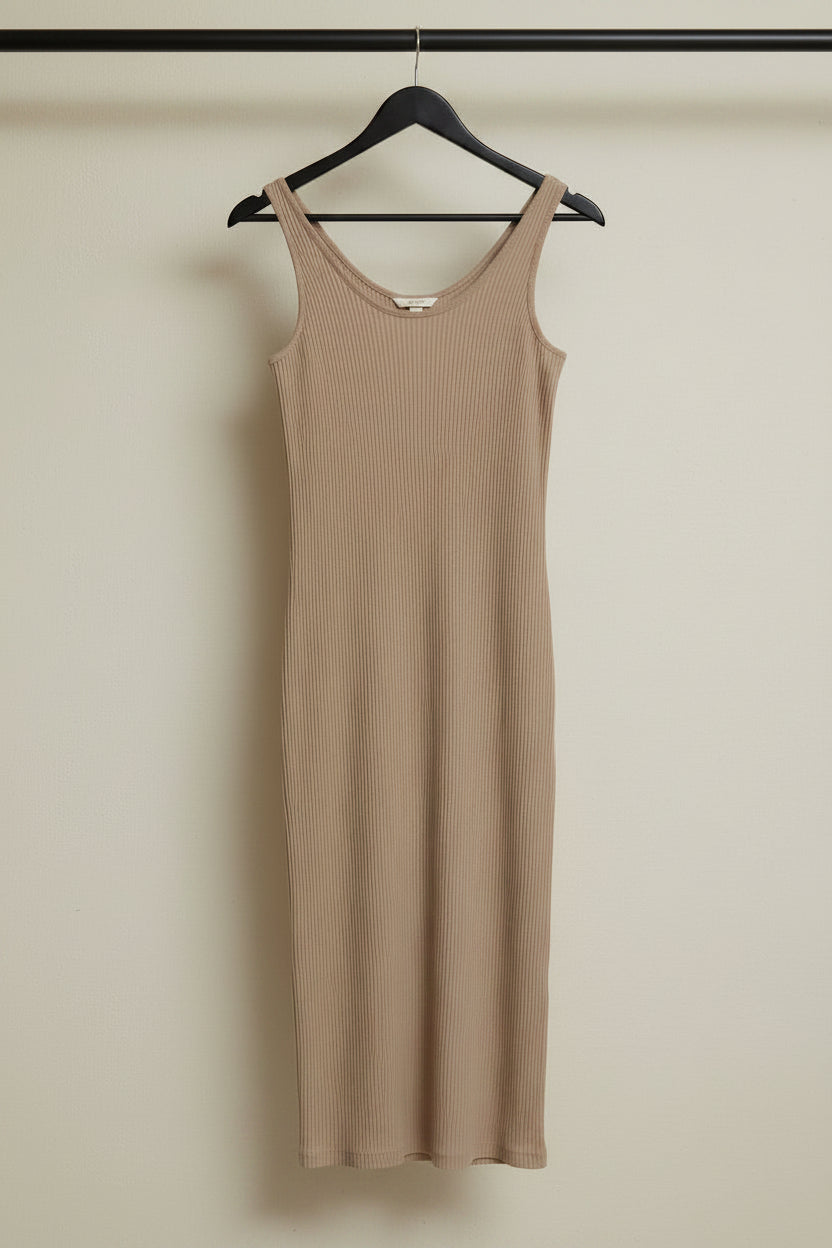 A sleeveless ribbed knit midi dress in a warm beige/tan color, hanging on a wooden hanger against a wrinkled white fabric backdrop.