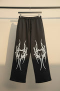 Black wide-leg sweatpants with a white tribal graphic print on both legs, featuring an elastic waistband and drawstring.