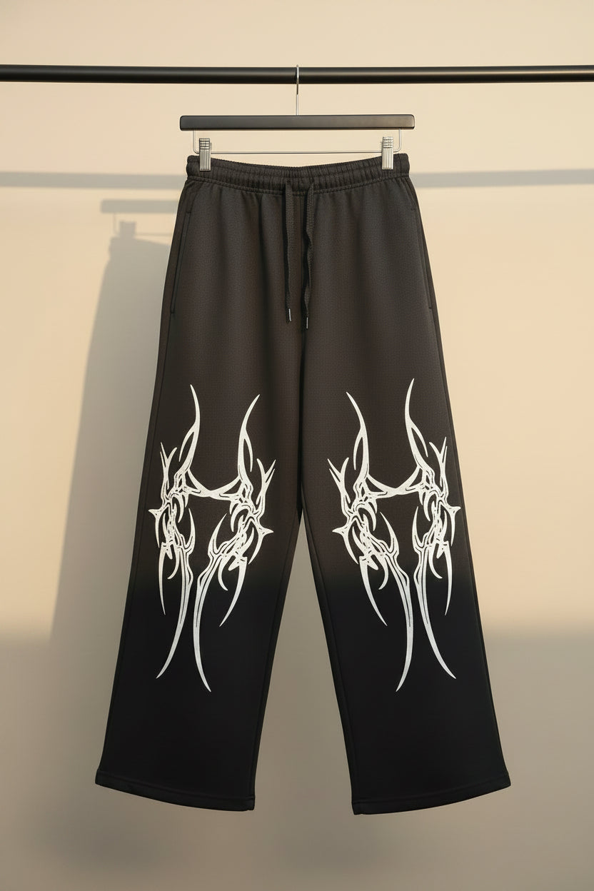 Black wide-leg sweatpants with a white tribal graphic print on both legs, featuring an elastic waistband and drawstring.
