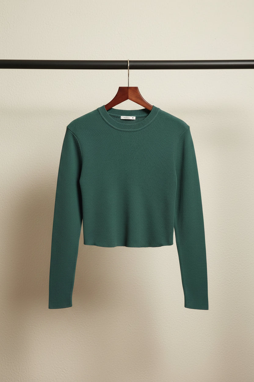 A dark green long-sleeve ribbed knit crop top sweater laid flat on a light gray background.