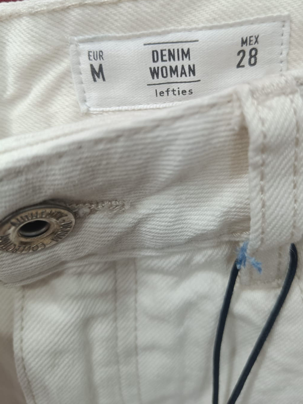 Close-up of the waistband of off-white denim jeans, showing the size and brand label 'DENIM WOMAN lefties' and a metal button closure.