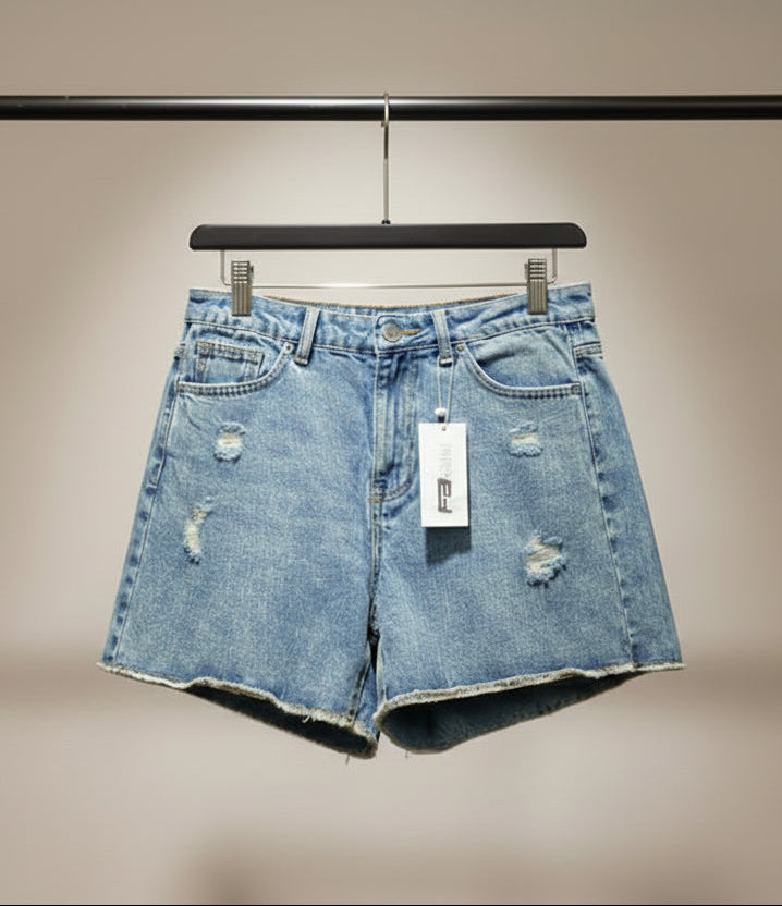 Light blue distressed denim shorts with a raw frayed hem, hanging on a wooden hanger against a solid red background. A white Hangar brand tag is attached to the waistband.