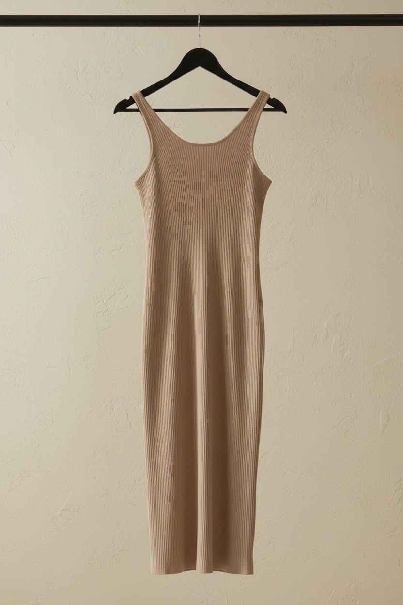 A beige ribbed knit sleeveless midi dress hanging on a wooden hanger against a white fabric backdrop.