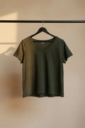 An olive green short-sleeve V-neck t-shirt hanging on a wooden hanger against a white fabric backdrop.