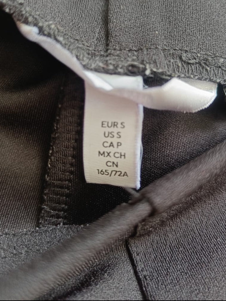 Close-up of a dark gray garment neck opening showing a white size tag with printed size information.