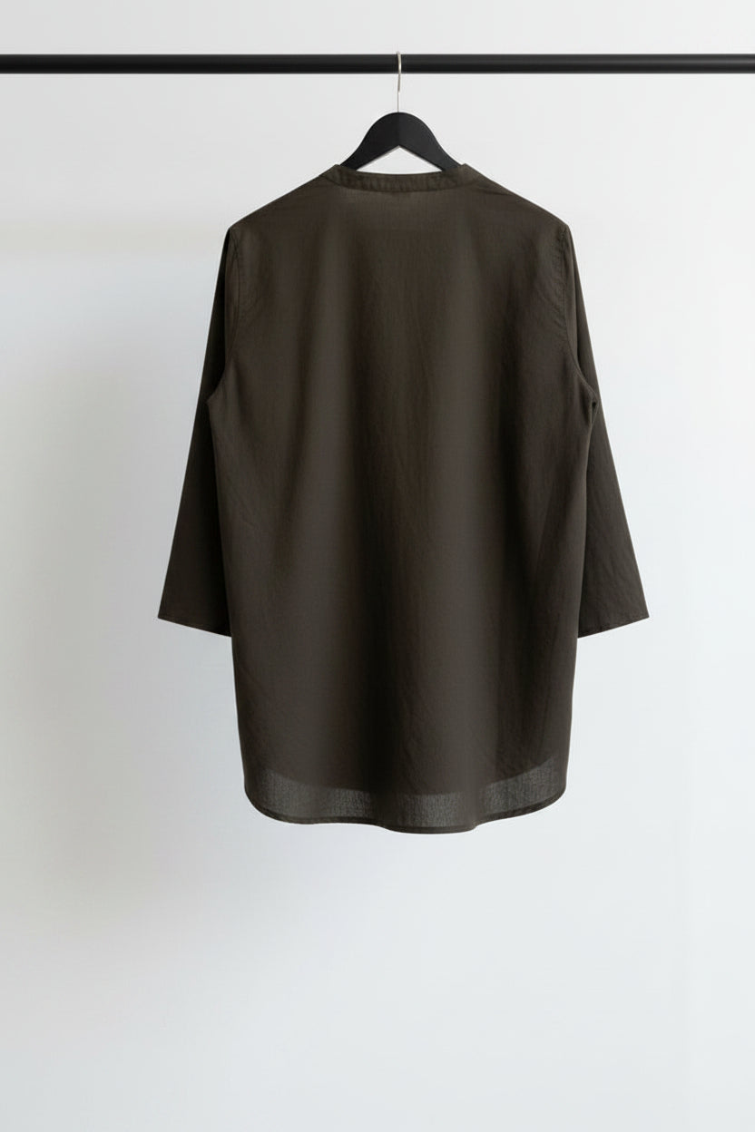 A dark brown three-quarter sleeve blouse hanging on a wooden hanger against a wrinkled white fabric backdrop.