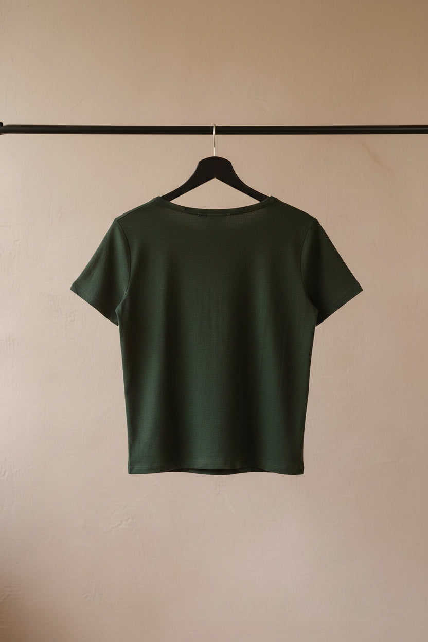 An olive green short-sleeve t-shirt hanging on a wooden hanger against a white fabric background.