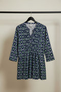 A women's long-sleeve tunic dress with a navy blue, green, and white ikat geometric pattern, featuring a button-up front and a matching fabric tie belt at the waist.