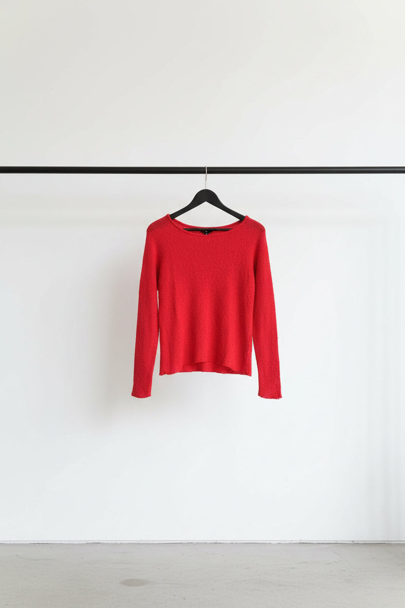 A bright red long-sleeve knit top with a fuzzy, textured fabric and a wide boat neckline, hanging on a wooden hanger against a white fabric backdrop.