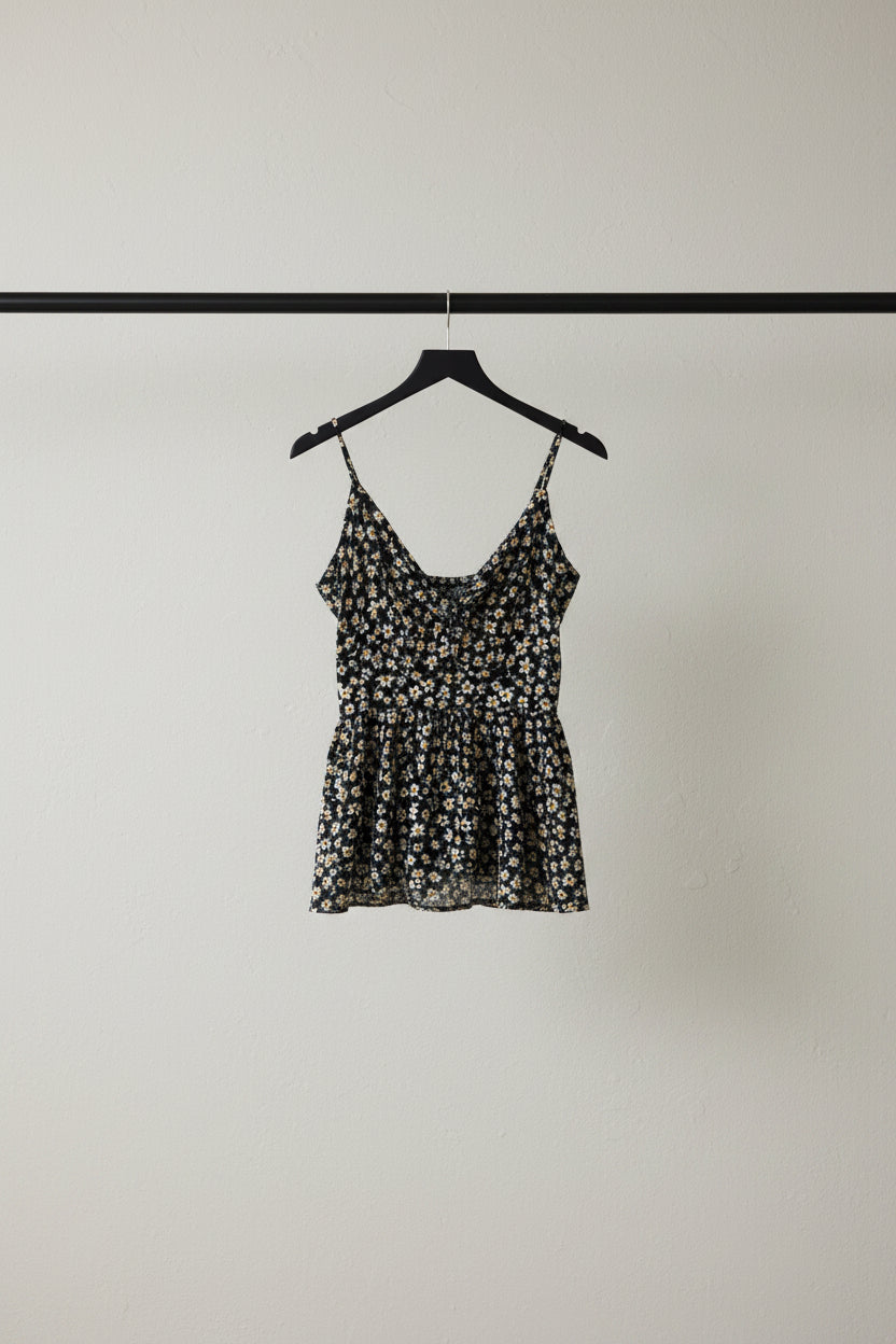 A sleeveless floral print camisole top with thin straps and a ruffled sweetheart neckline, laid flat on a white fabric background.