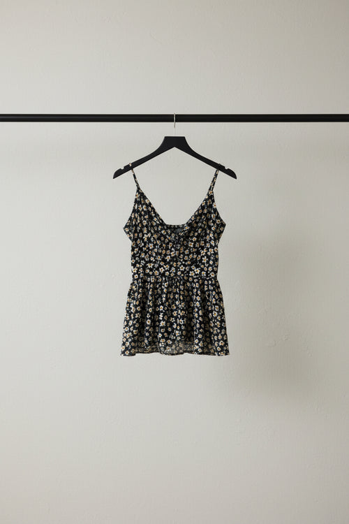 A sleeveless floral print camisole top with thin straps and a ruffled sweetheart neckline, laid flat on a white fabric background.