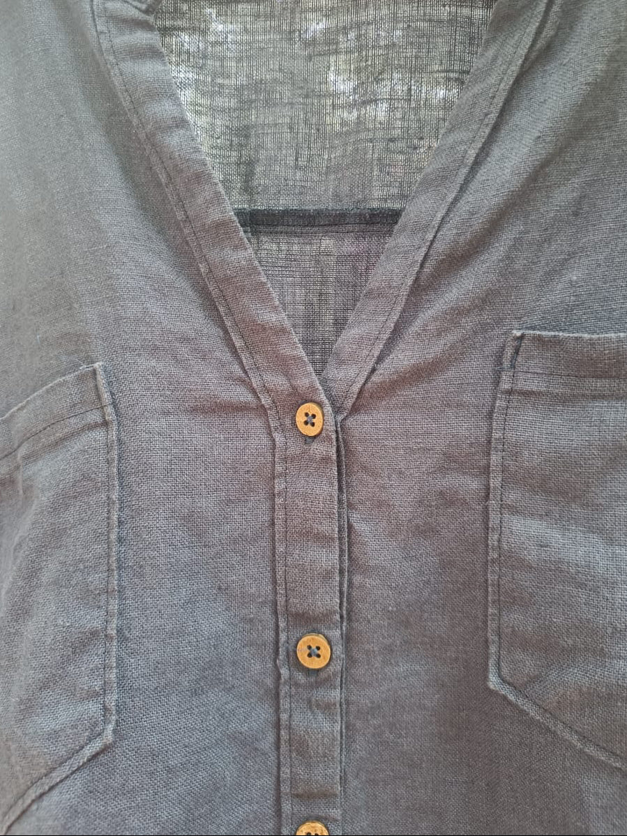 Close-up of a gray linen button-up shirt with brown buttons, featuring a split V-neck and two chest pockets.